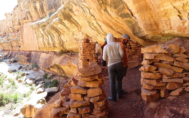 Two people explore an old dwelling built into a rock wall.